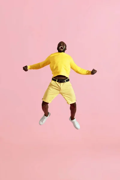 Jump. Black man jumping in air and screaming on pink background — Stock Photo, Image