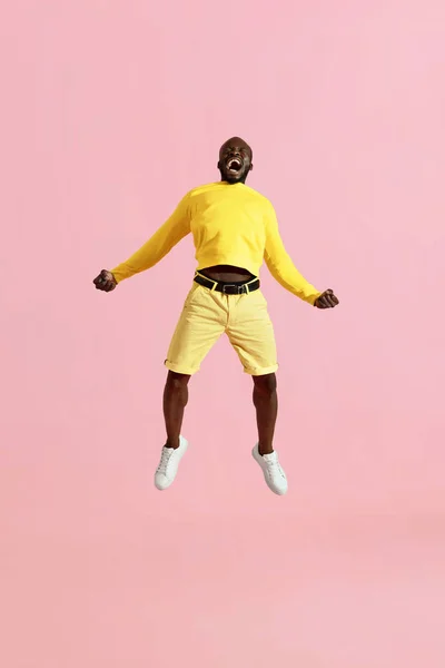 Jump. Black man jumping in air and screaming on pink background — Stock Photo, Image