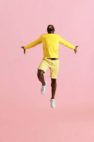 Salta. Hombre negro saltando en el aire y gritando sobre fondo rosa — Foto de Stock