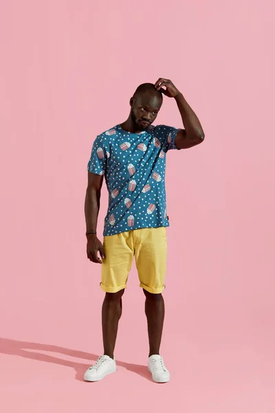 Fashion. Black man in stylish clothes on pink background