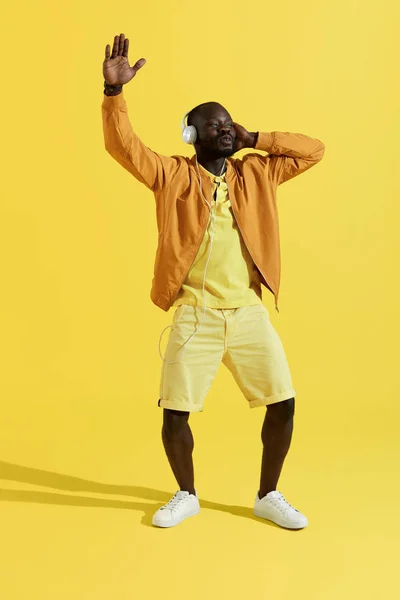 Hombre con auriculares y ropa de moda escuchando música, cantando — Foto de Stock