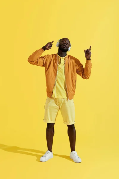 Hombre con auriculares y ropa de moda escuchando música, cantando — Foto de Stock