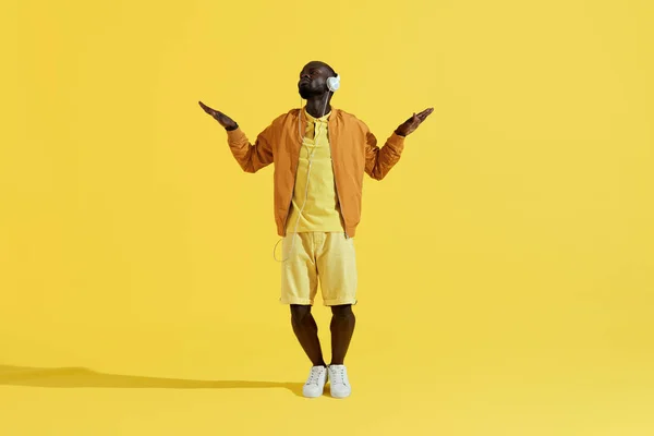 Man in headphones listening music, dancing on yellow background — Stock Photo, Image