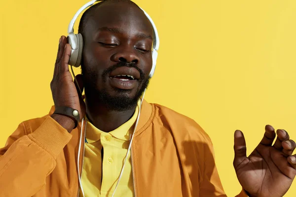 Man in headphone listening music, singing on yellow background — Stok Foto