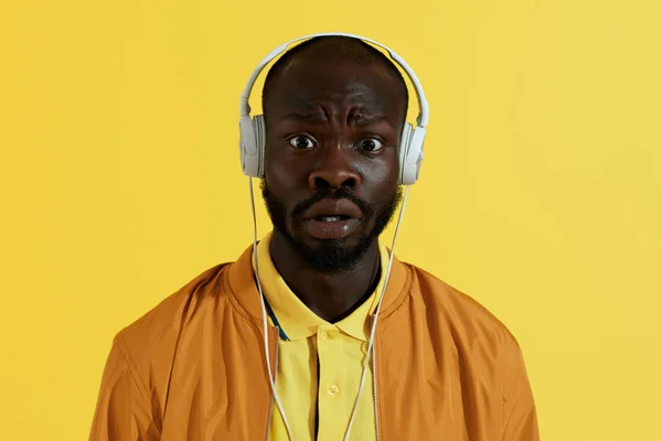 Surprised man in headphones listening music on yellow background — Stock Photo, Image