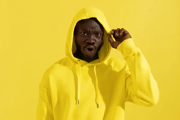 色の背景に面白い顔を作る黄色のパーカーの黒人男性 — ストック写真