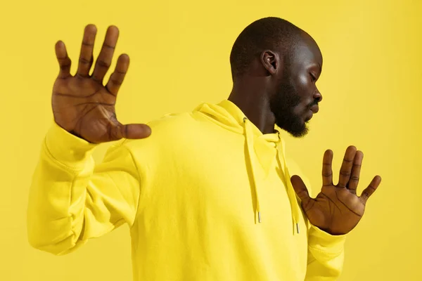 Modeporträt schwarzer Mann in gelbem Kapuzenpulli auf farbigem Hintergrund — Stockfoto