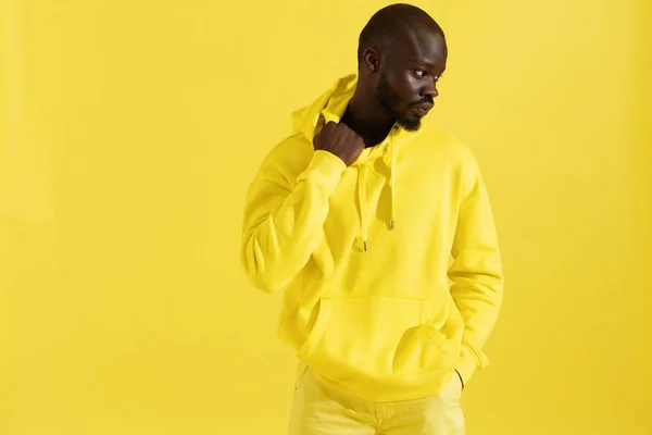 Fashion portrait black man in yellow hoodie on color background