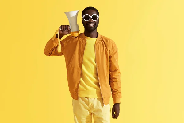 Retrato de moda de hombre negro sonriente con megáfono en amarillo — Foto de Stock