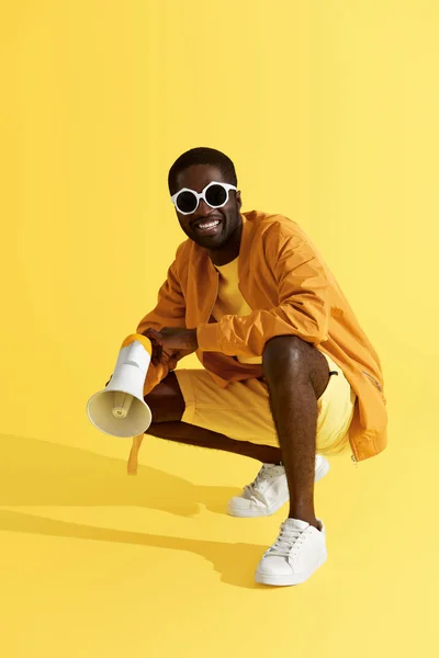 Fashion. Smiling black man in stylish clothes with megaphone — Stock Photo, Image