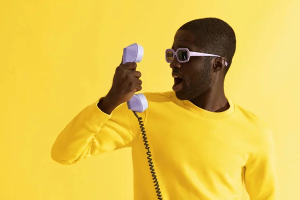 노란색 배경에 전화와 선글라스에 놀란 남자 — 스톡 사진