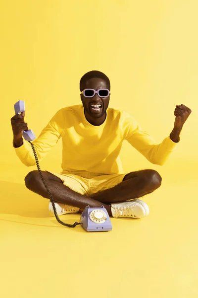 Feliz hombre emocionado con teléfono celebrando sobre fondo amarillo — Foto de Stock