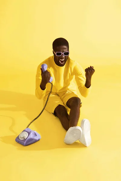 Feliz hombre emocionado con teléfono celebrando sobre fondo amarillo — Foto de Stock