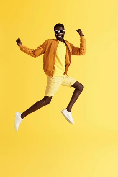 跳。快乐的人在空中跳跃，在黄色背景上大笑 — 图库照片