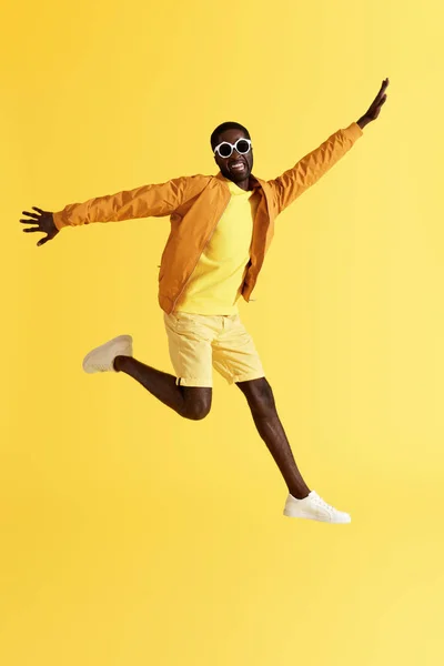 Salta. Homem feliz pulando no ar e rindo no fundo amarelo — Fotografia de Stock