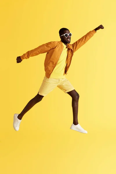 Salta. Hombre saltando, volando como superhéroe sobre fondo amarillo — Foto de Stock