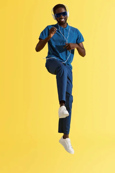 音楽を聴くヘッドフォンの男、黄色の背景で踊る — ストック写真