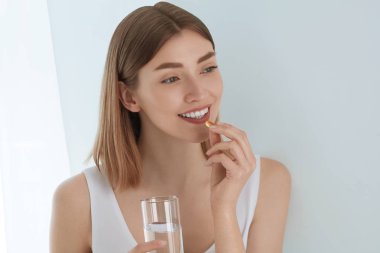 Kadın kapalı tatlı su bardağı ile vitamin hapı alarak
