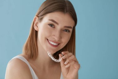 Teeth whitening. Woman with healthy teeth using removable braces clipart