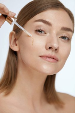 Cilt bakımı. Güzellik yüzüne serum veya yüz yağı uygulayan kadın