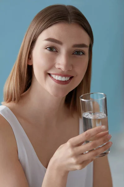 Uśmiechnięta kobieta ze szklanką wody w pomieszczeniu portret — Zdjęcie stockowe