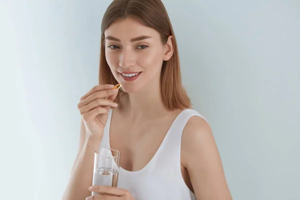 Vrouw neemt vitamine pil met glas zoet water binnenshuis — Stockfoto