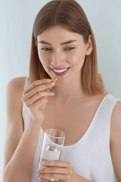 실내에서 담수 한 잔으로 비타민 알약을 복용하는 여성 — 스톡 사진