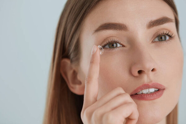 Contact eye lens. Woman applying eye contacts on eyes closeup