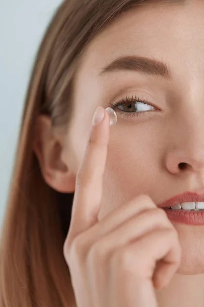 Contact eye lens. Woman applying eye contacts on eyes closeup