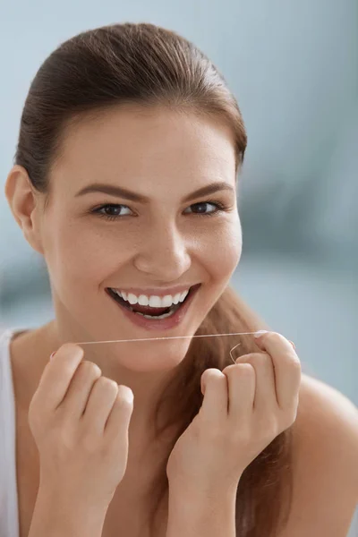 Cuidado dental. Mujer sonriente limpiando dientes blancos con hilo dental —  Fotos de Stock