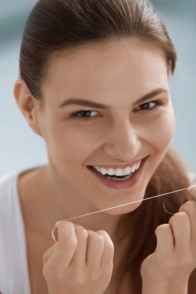 Cuidado dental. Mujer sonriente limpiando dientes blancos con hilo dental —  Fotos de Stock