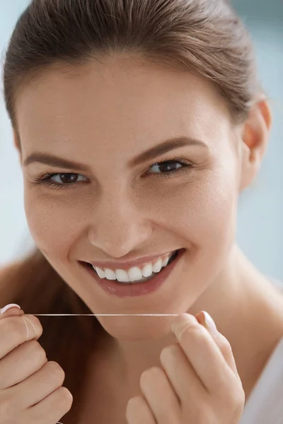 Hilo dental. Mujer sonriente limpiando dientes blancos con hilo dental — Foto de Stock