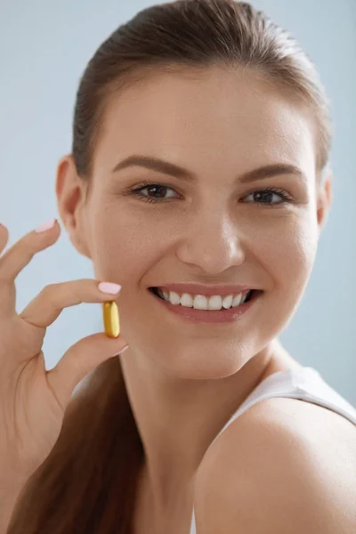 Вітамін. Усміхнена жінка з омега-3 таблетки, риб'ячий жир таблетки — стокове фото