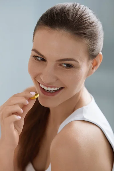 Vitamina. Mujer sonriente tomando la píldora omega, suplemento de aceite de pescado — Foto de Stock