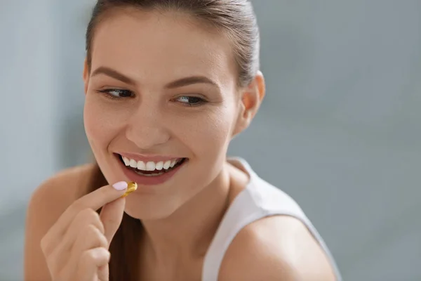 Vitamina. Mujer sonriente tomando la píldora omega, suplemento de aceite de pescado — Foto de Stock