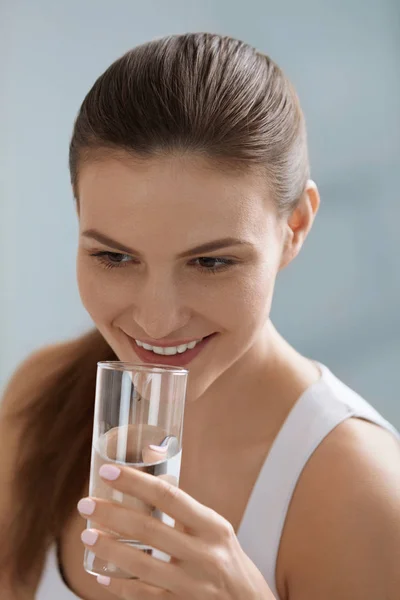 Bebe agua. Mujer sonriente sosteniendo agua pura fresca en vidrio — Foto de Stock