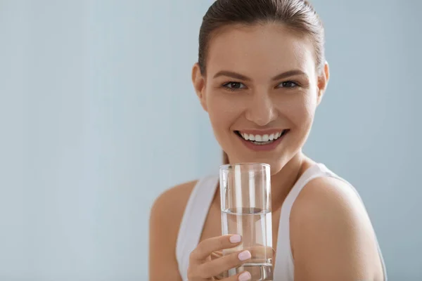 Bebe água. Mulher sorridente segurando água pura fresca em vidro — Fotografia de Stock