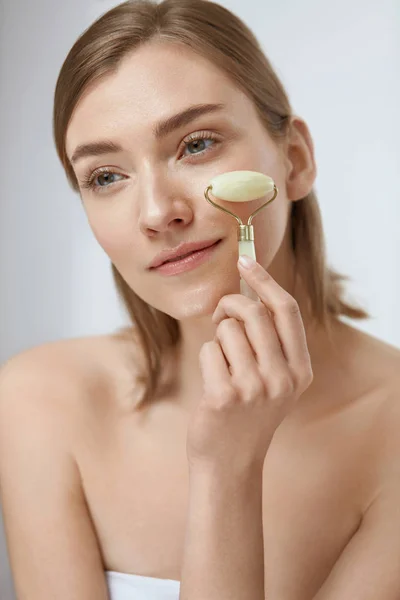 Cuidado de la piel belleza. Mujer usando rodillo de jade para masaje facial — Foto de Stock