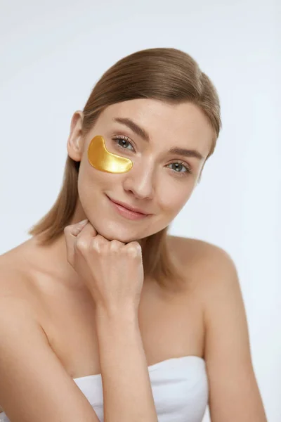 Cuidado de la piel. Cara de mujer con parche de oro debajo del ojo, máscara de belleza — Foto de Stock