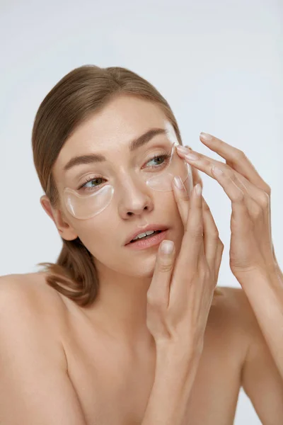 Cuidado de la piel. Mujer aplicando máscara de parche de belleza bajo los ojos —  Fotos de Stock