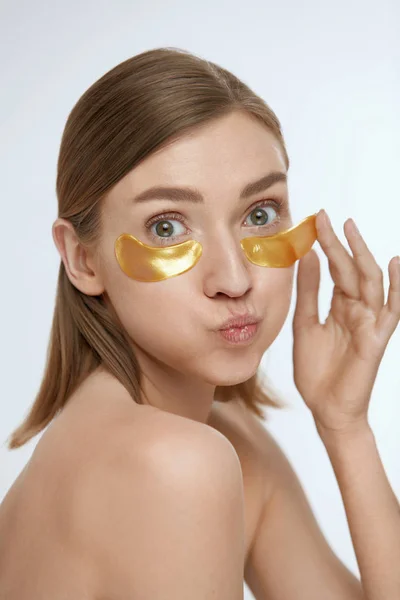 スキンケア。目の下にゴールドパッチ、美容マスクを持つ女性 — ストック写真