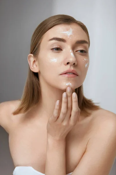 Cuidado de la piel. Mujer aplicando crema facial en belleza cara primer plano — Foto de Stock