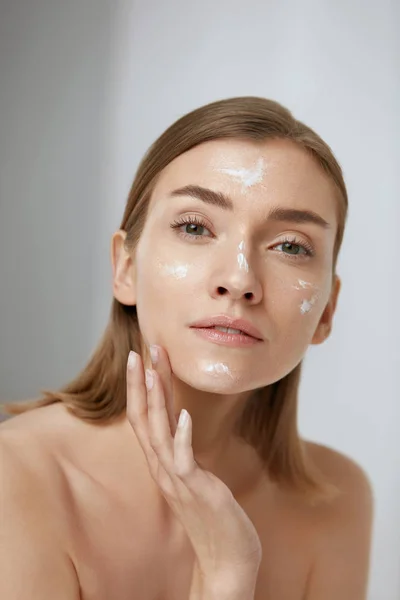 Cuidado de la piel. Mujer aplicando crema facial en belleza cara primer plano —  Fotos de Stock