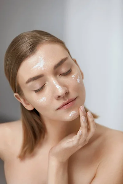 Cuidado com a pele. Mulher aplicando creme facial na beleza rosto closeup — Fotografia de Stock