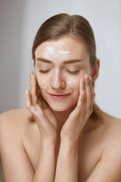 Cuidado de la piel. Mujer aplicando limpiador facial en el primer plano de la cara —  Fotos de Stock