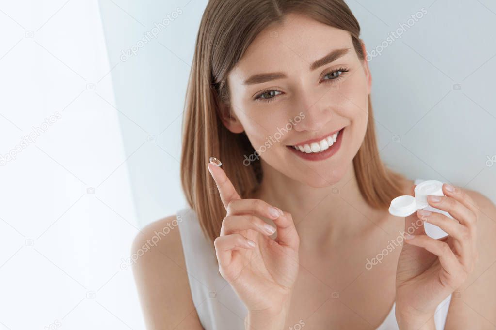 Eye lens. Smiling woman with contact eye lenses and container