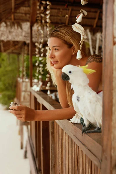 Lächelnde Frau mit Papagei im tropischen Kurort im Sommer — Stockfoto