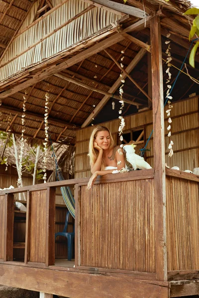 Frau mit Papagei in einem Bungalow im tropischen Resort im Sommer — Stockfoto