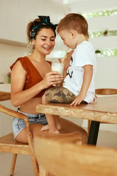 Child drinking healthy drink, vegan milk with mother in kitchen — Stock Photo, Image