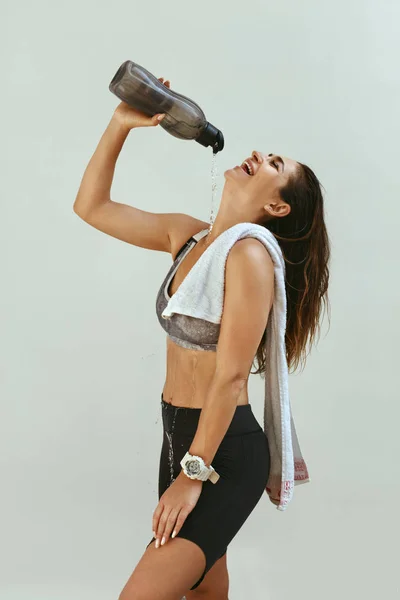 Mulher em roupas esportivas derramando água no corpo após o treino — Fotografia de Stock